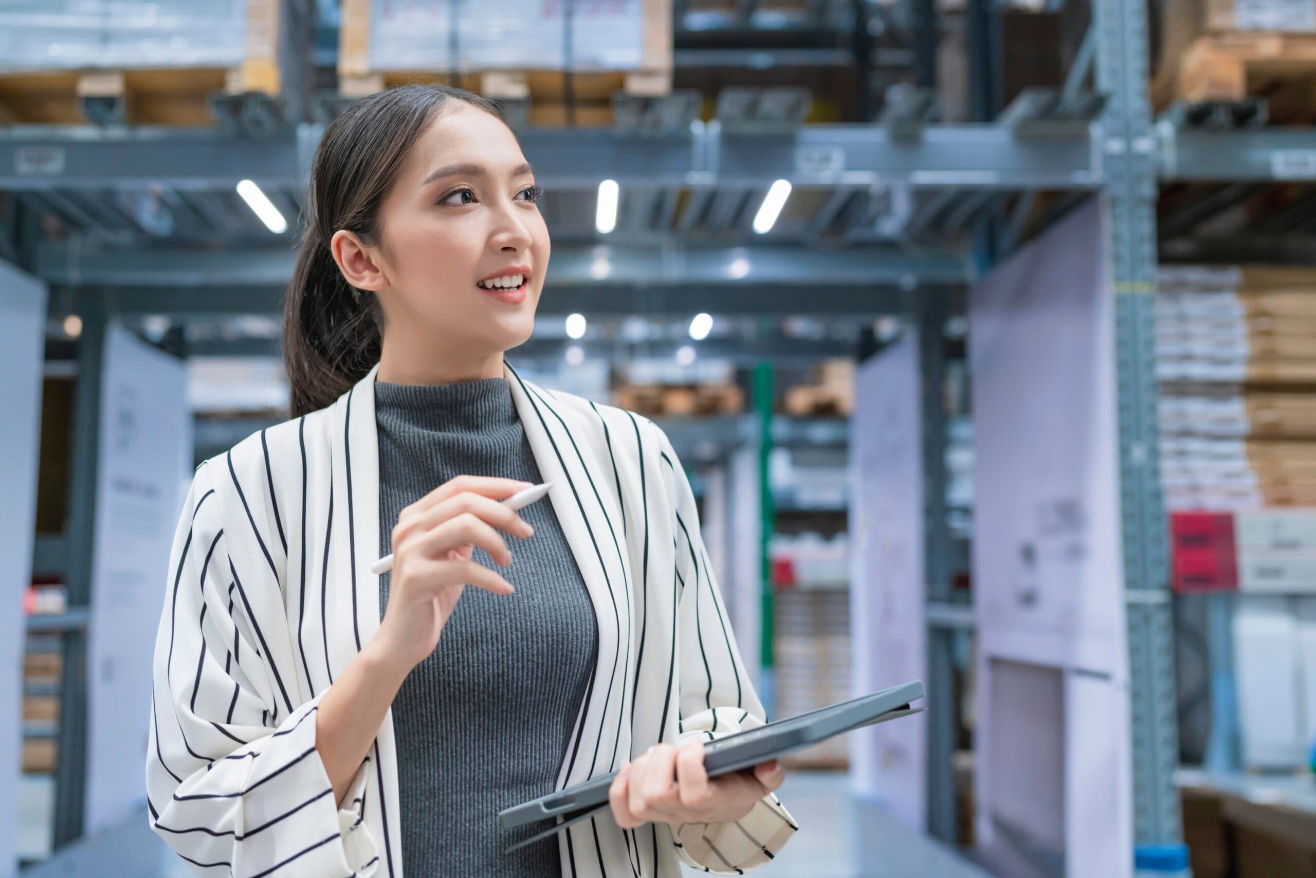 Portrait of asian woman business owner using digital tablet checking amount of stock product inventory on shelf at distribution warehouse factory.logistic business shipping and delivery service