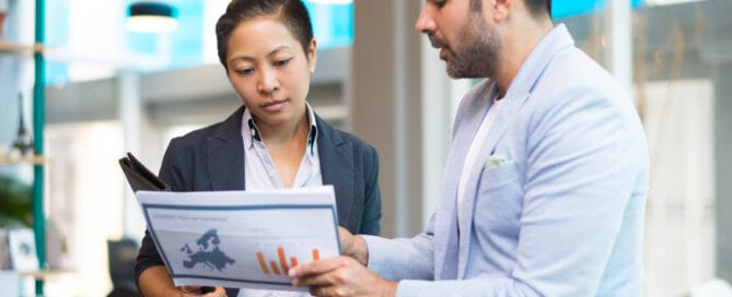 Positive Latin man showing report to Asian woman with folder. Hispanic businessman explaining data to female colleague. Explanation concept
